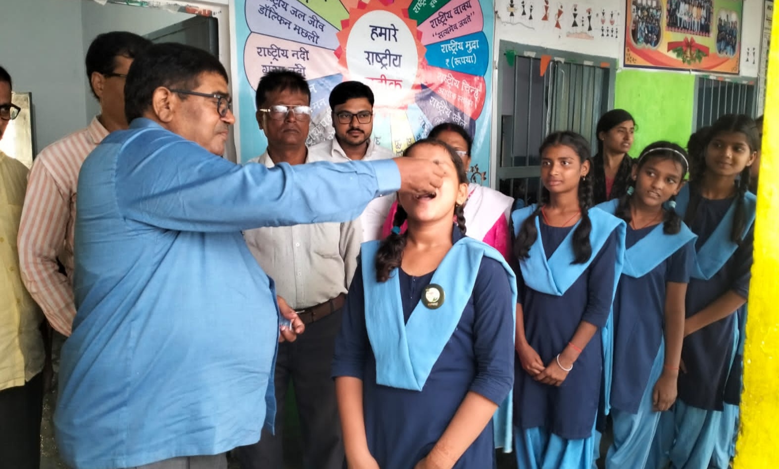 बच्चे को दवा खिलाते अधिकारी बच्चे को दवा खिलाते अधिकारी