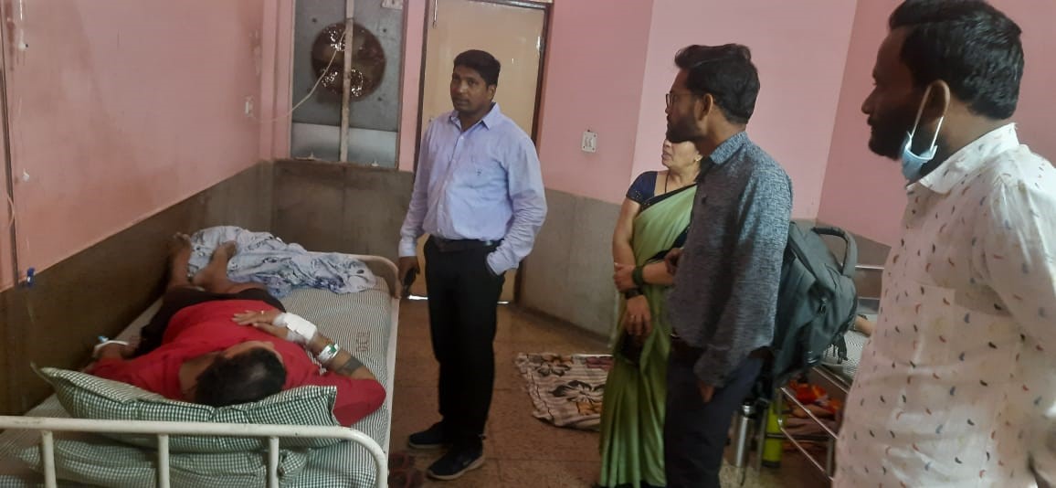 मोमोज खाकर अस्पताल में भर्ती मरीज को देखते हुए स्वजन व अधिकारियों की टीम।