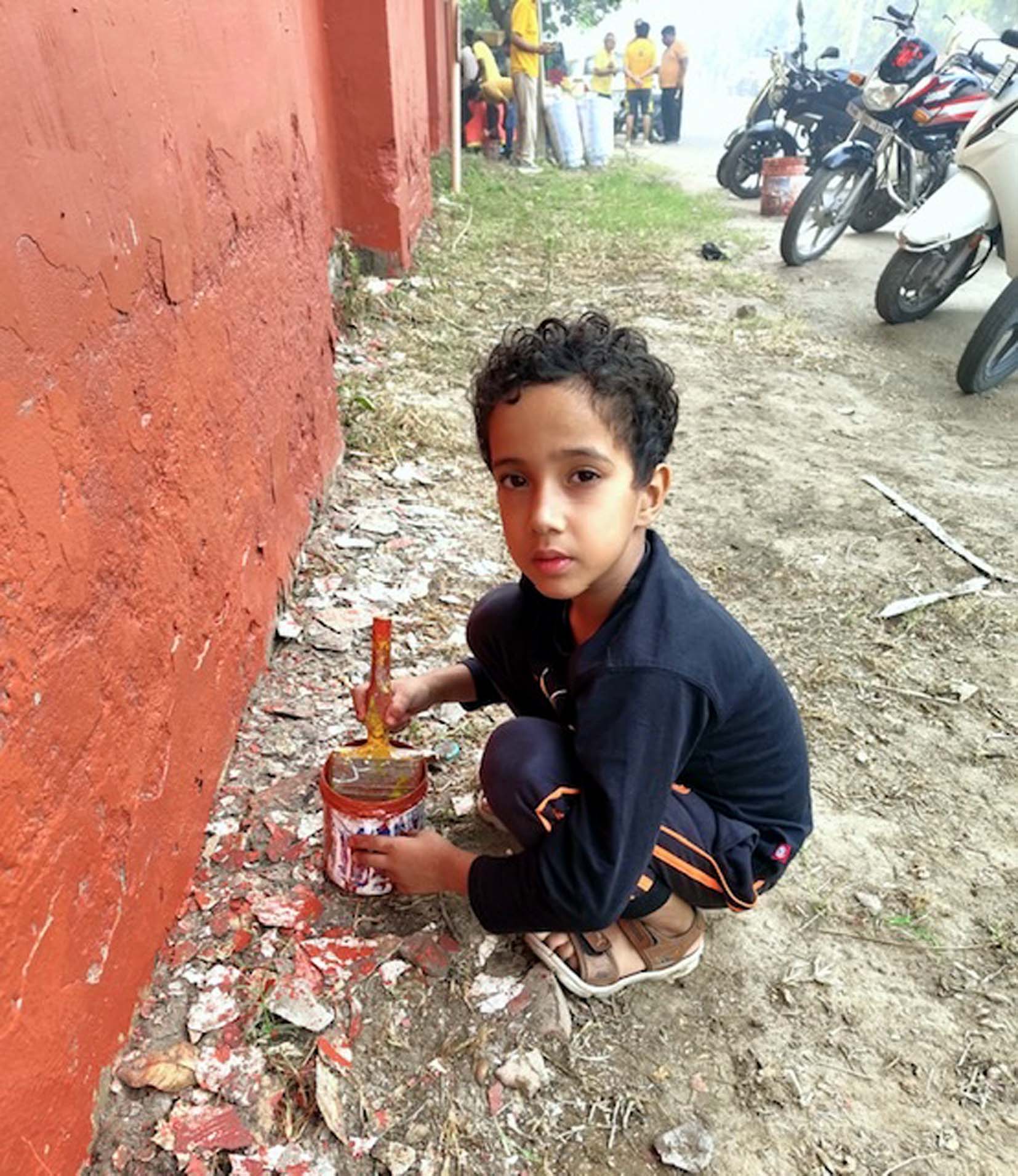 दीवार पर पेंटिंग अभियान में साथ आया छोटा बच्चा।