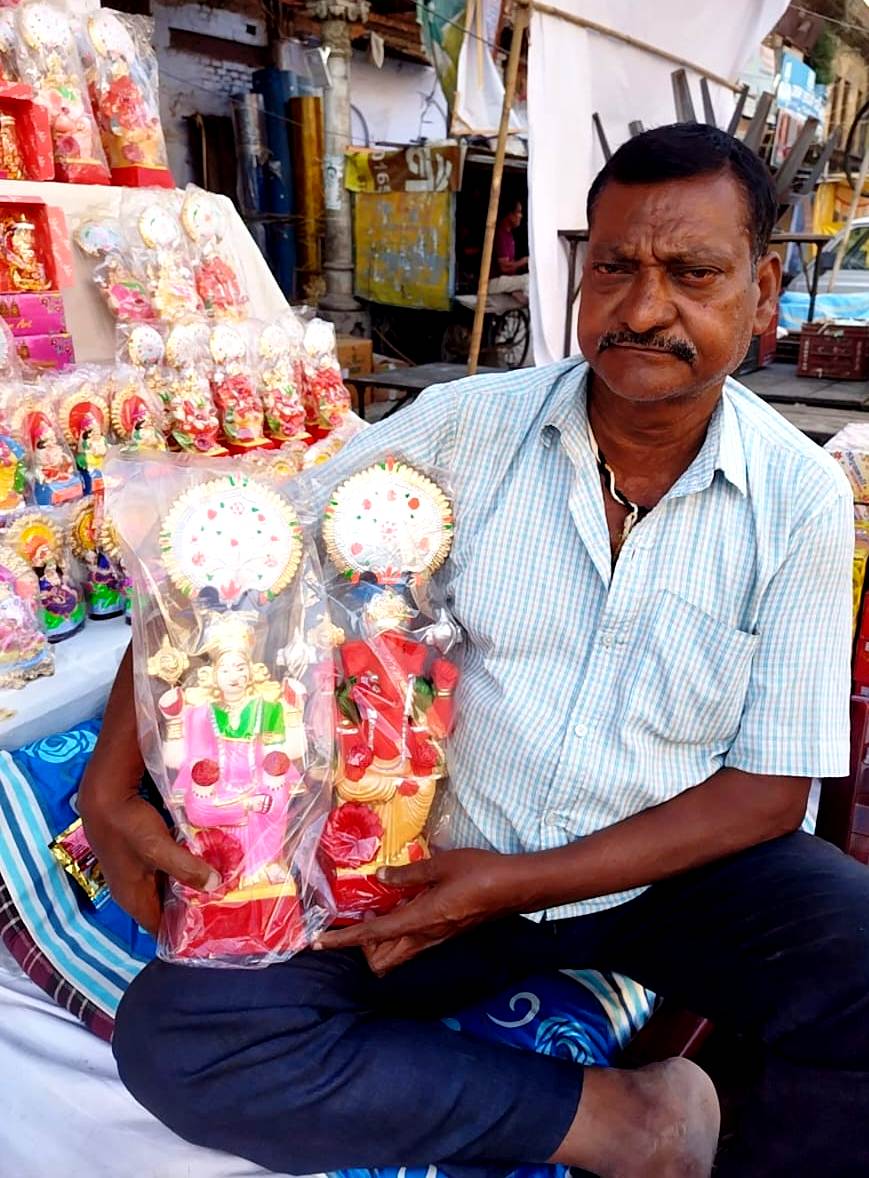मिट्टी की बनी मूर्तियों को दिखाता दुकानदार