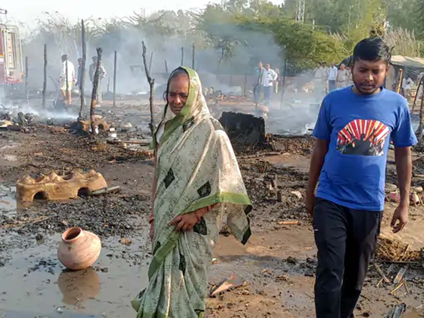 जलती झुग्गियां देखती महिला। जलती झुग्गियां देखती महिला।