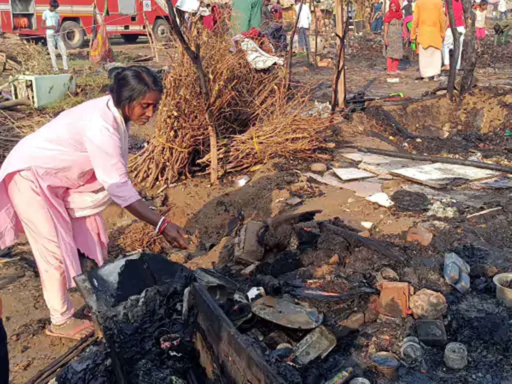 जलती झुग्गियां देखती महिला। जलती झुग्गियां देखती महिला।