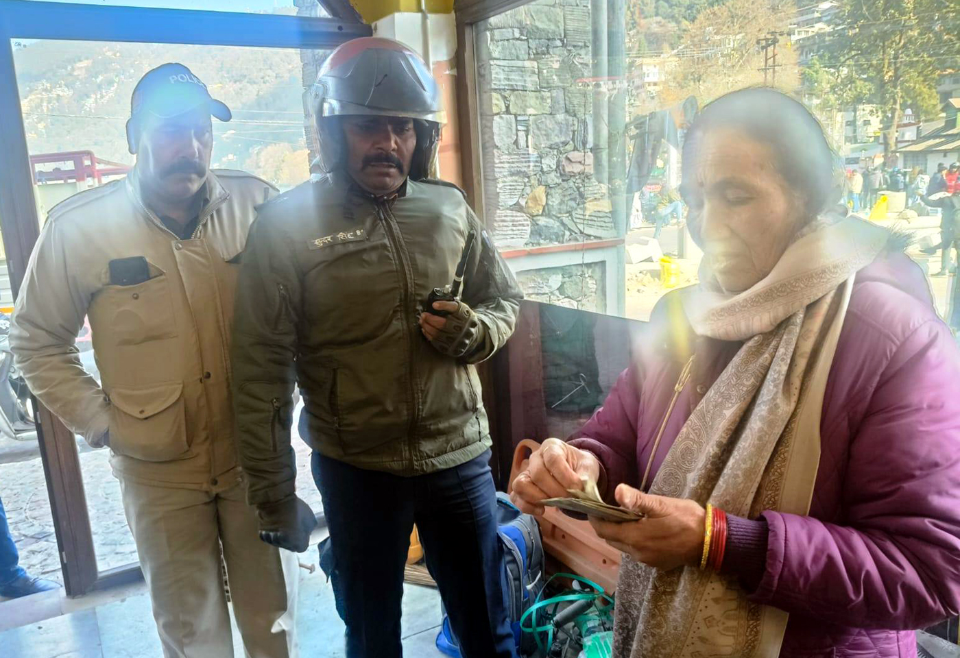 महिला को उसका बैग लौटाते पुलिस कर्मी। महिला को उसका बैग लौटाते पुलिस कर्मी।