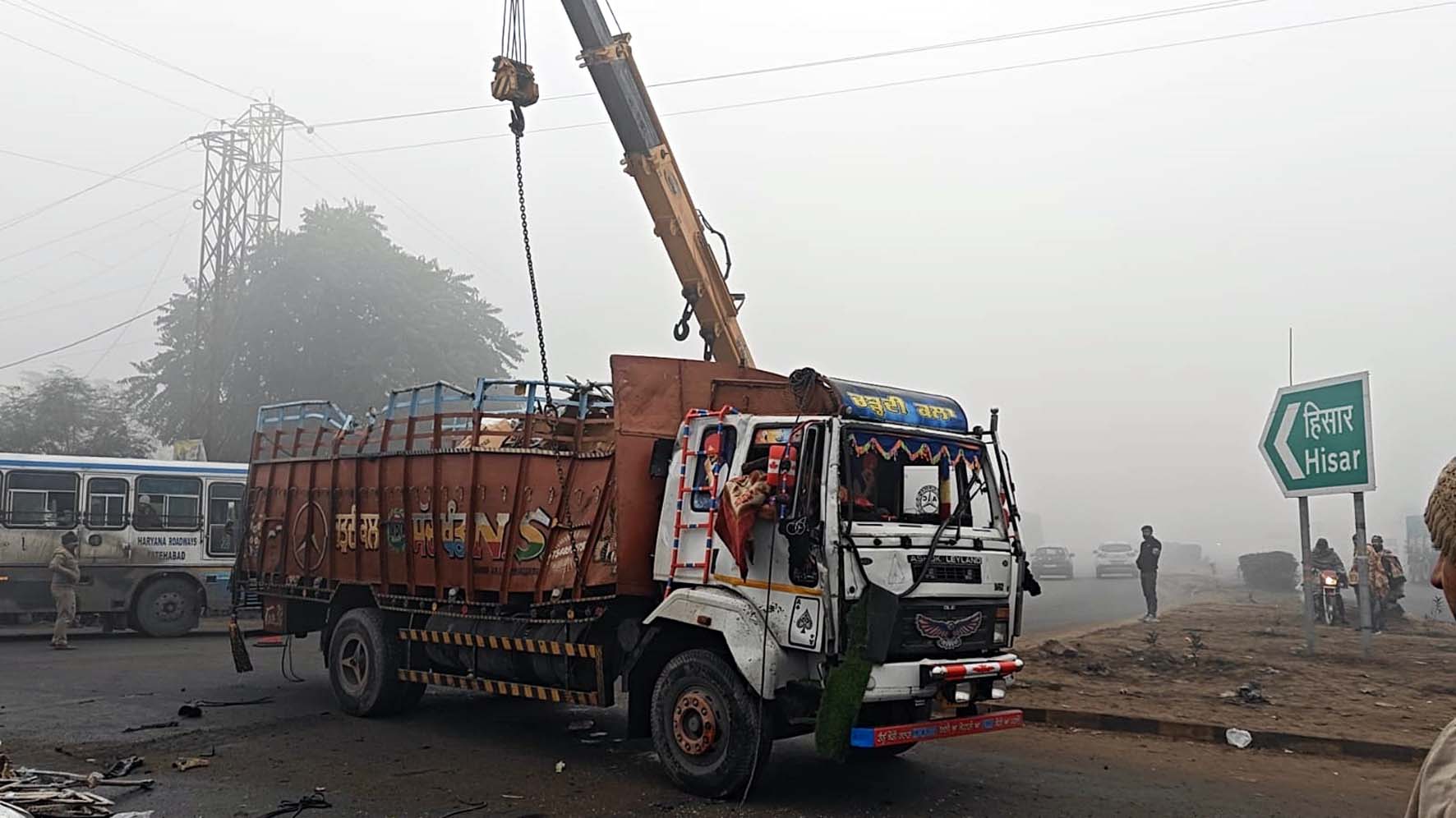 ट्रक को क्रेन की सहायता से सीधा करते लोग। ट्रक को क्रेन की सहायता से सीधा करते लोग।