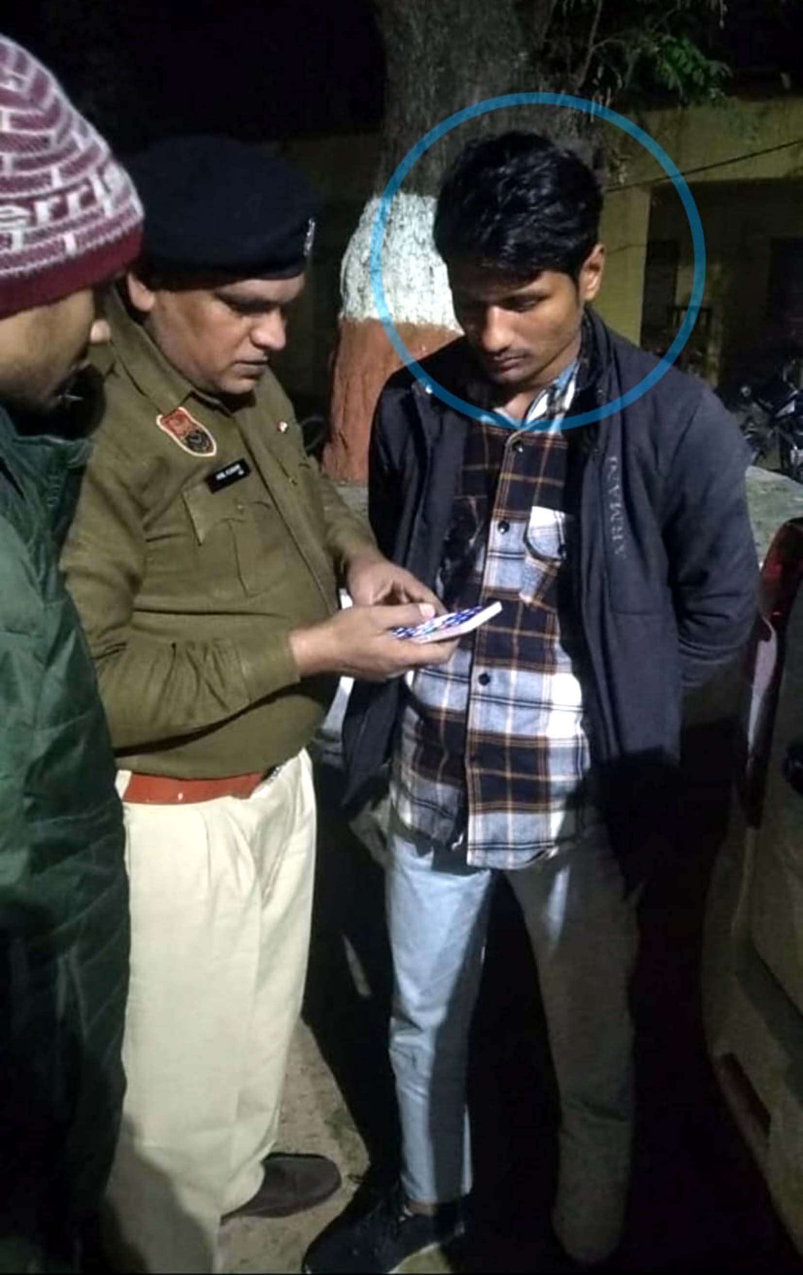 पकड़े गए आरोपी के फोन की जांच करते पुलिस अधिकारी। पकड़े गए आरोपी के फोन की जांच करते पुलिस अधिकारी।