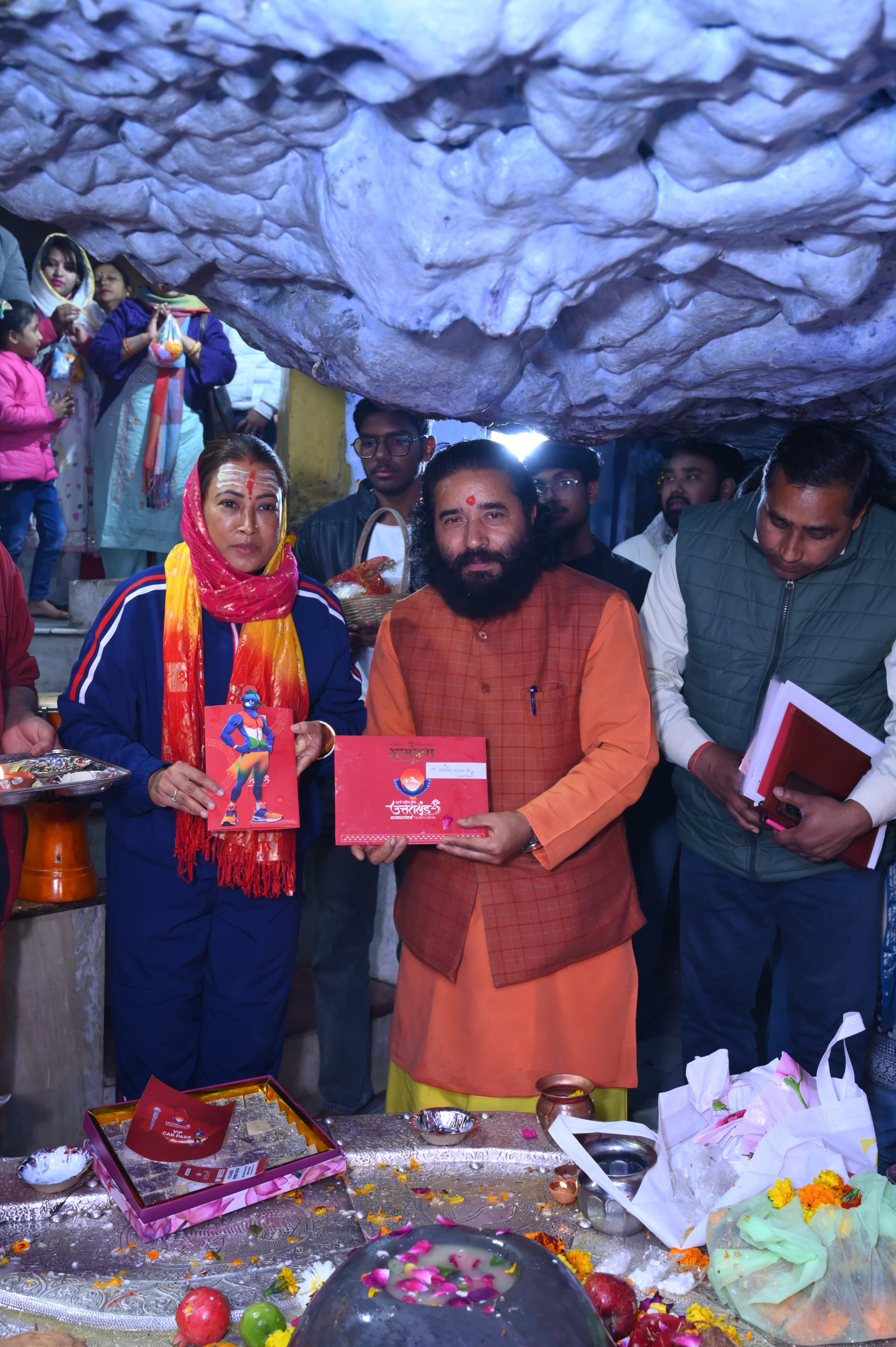 उत्तराखंड की खेल मंत्री रेखा आर्या टपकेश्वर महादेव मंदिर में पंडित विपिन जोशी और पुजारी को राष्ट्रीय खेल का निमंत्रण पत्र सौंपती।