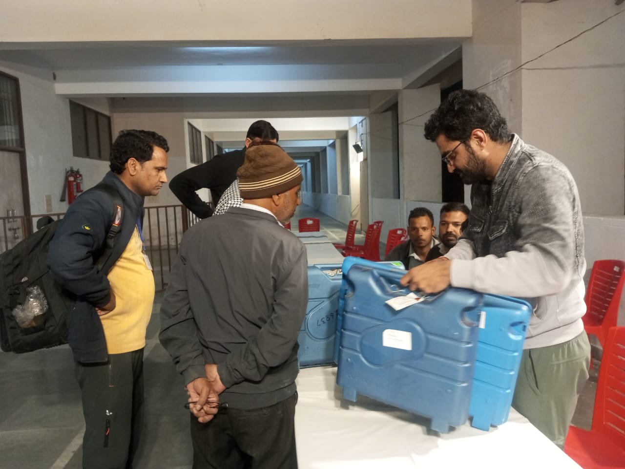 ईवीएम मशीन बंद करते हुए कर्मचारी ईवीएम मशीन बंद करते हुए कर्मचारी