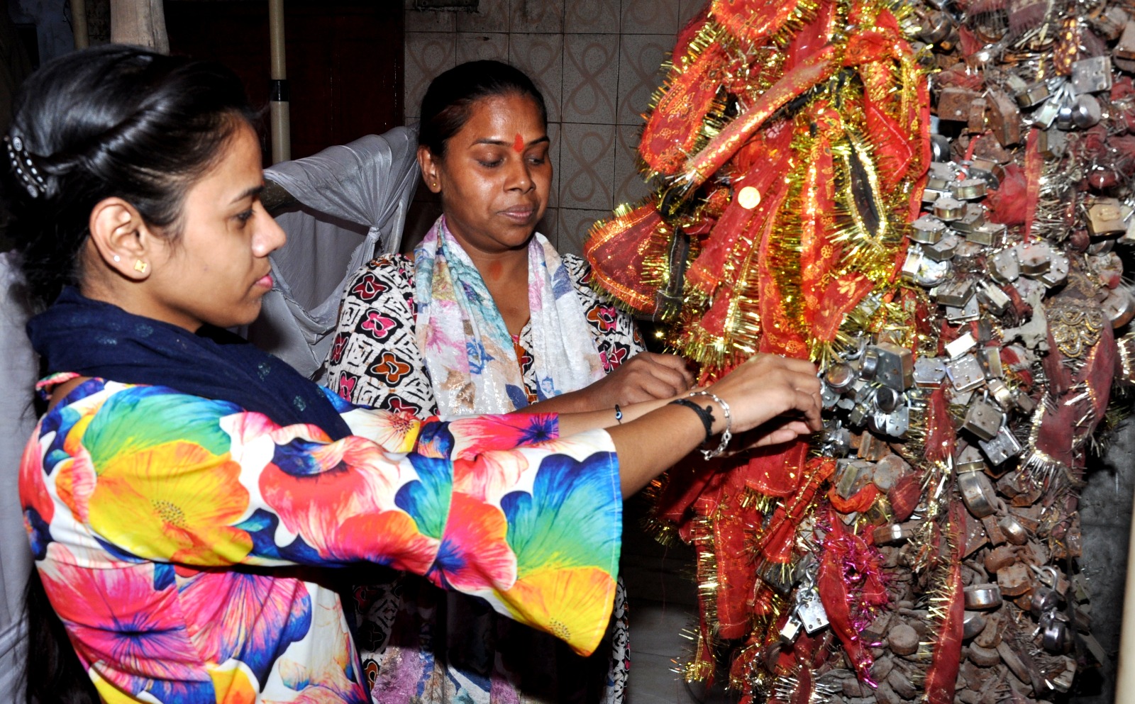 मंदिर प्रांगण में मनोकामना मांग कर ताला बांधती महिला श्रद्धालु मंदिर प्रांगण में मनोकामना मांग कर ताला बांधती महिला श्रद्धालु
