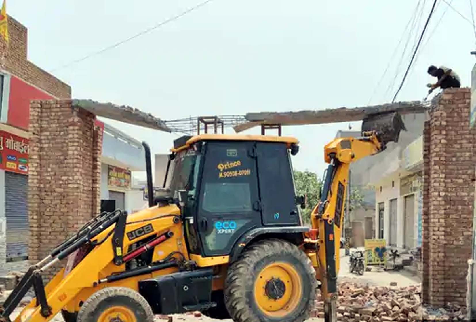 लचके स्वागत द्वार को जेसीबी से गिराते मजदूर। लचके स्वागत द्वार को जेसीबी से गिराते मजदूर।