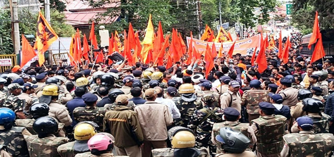 पुलिस बलों की मौजूदगी में भगवा झंडों के साथ प्रदर्शनकारी।