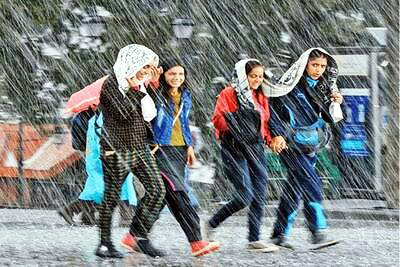 नैनीताल में बारिश आने पर बच कर निकलती युवतियां।