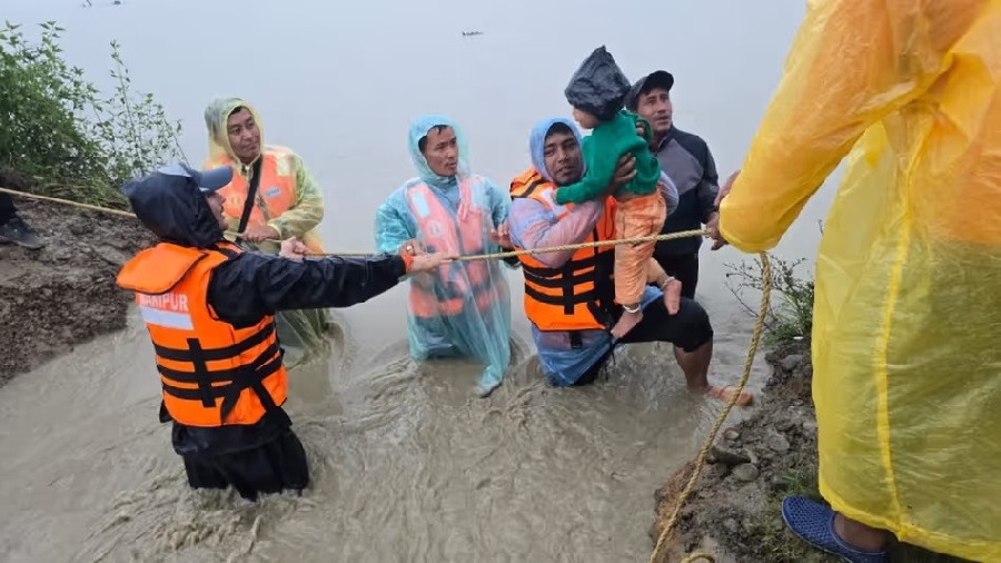 मणिपुरः बाढ़ में फंसे लोगों को सुरक्षित स्थानों पर पहुंचाते विभिन्न एजेंसियों के कर्मी।
