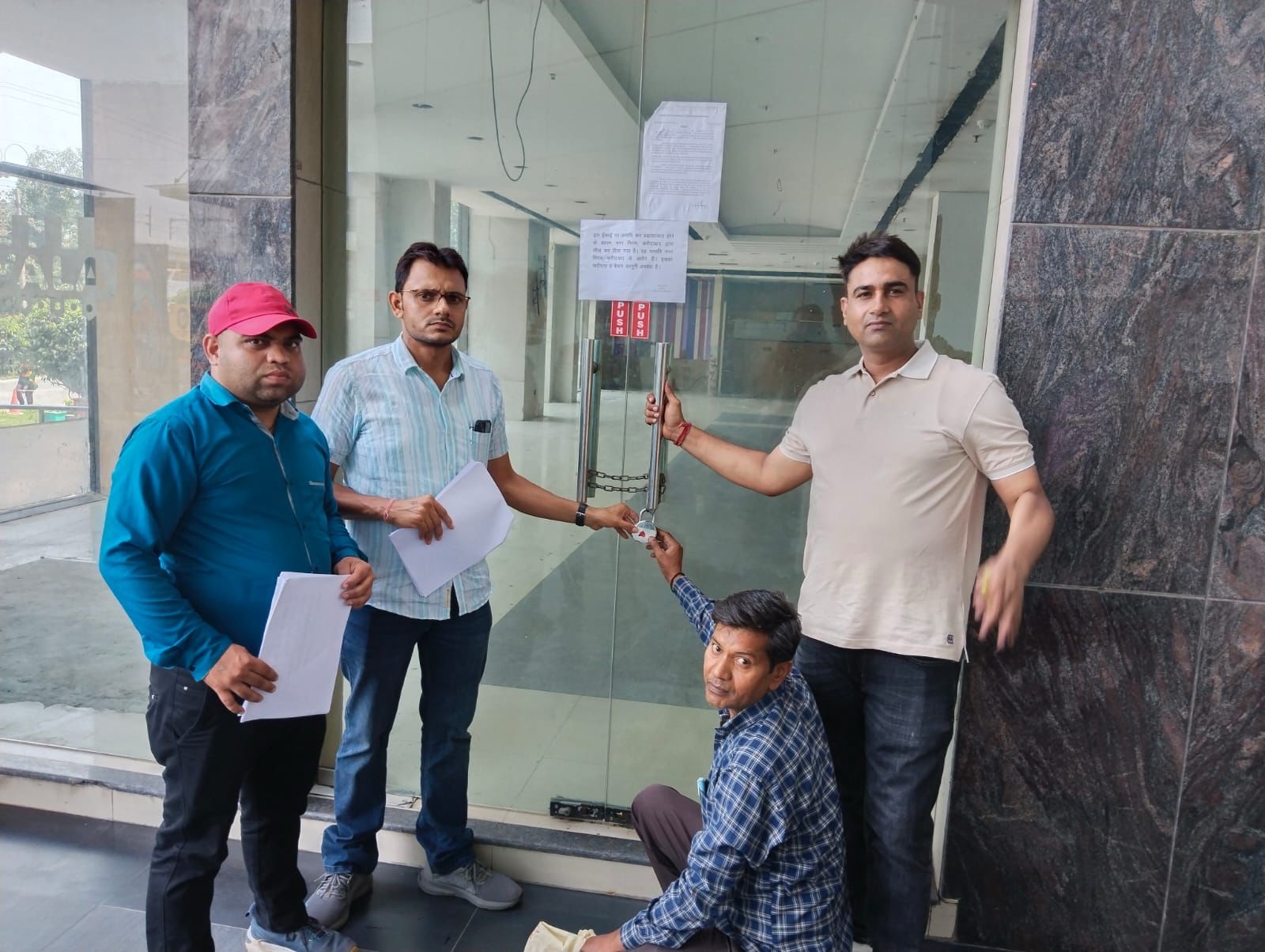 संपत्ति को सील करते निगम कर्मचारी