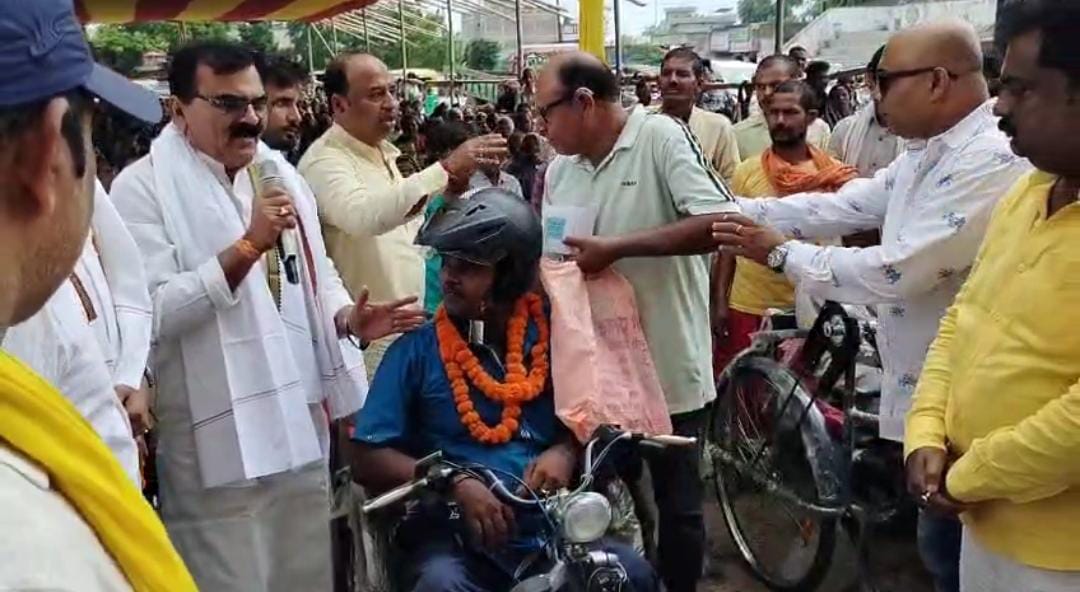 दिव्यांग को सहायता उपकरण देते लोग दिव्यांग को सहायता उपकरण देते लोग