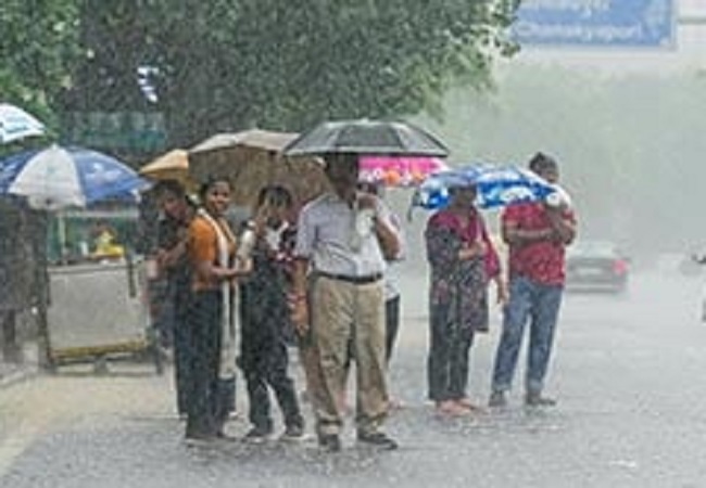 बारिश में खड़े लाेगाें की फाइल फाेटाे