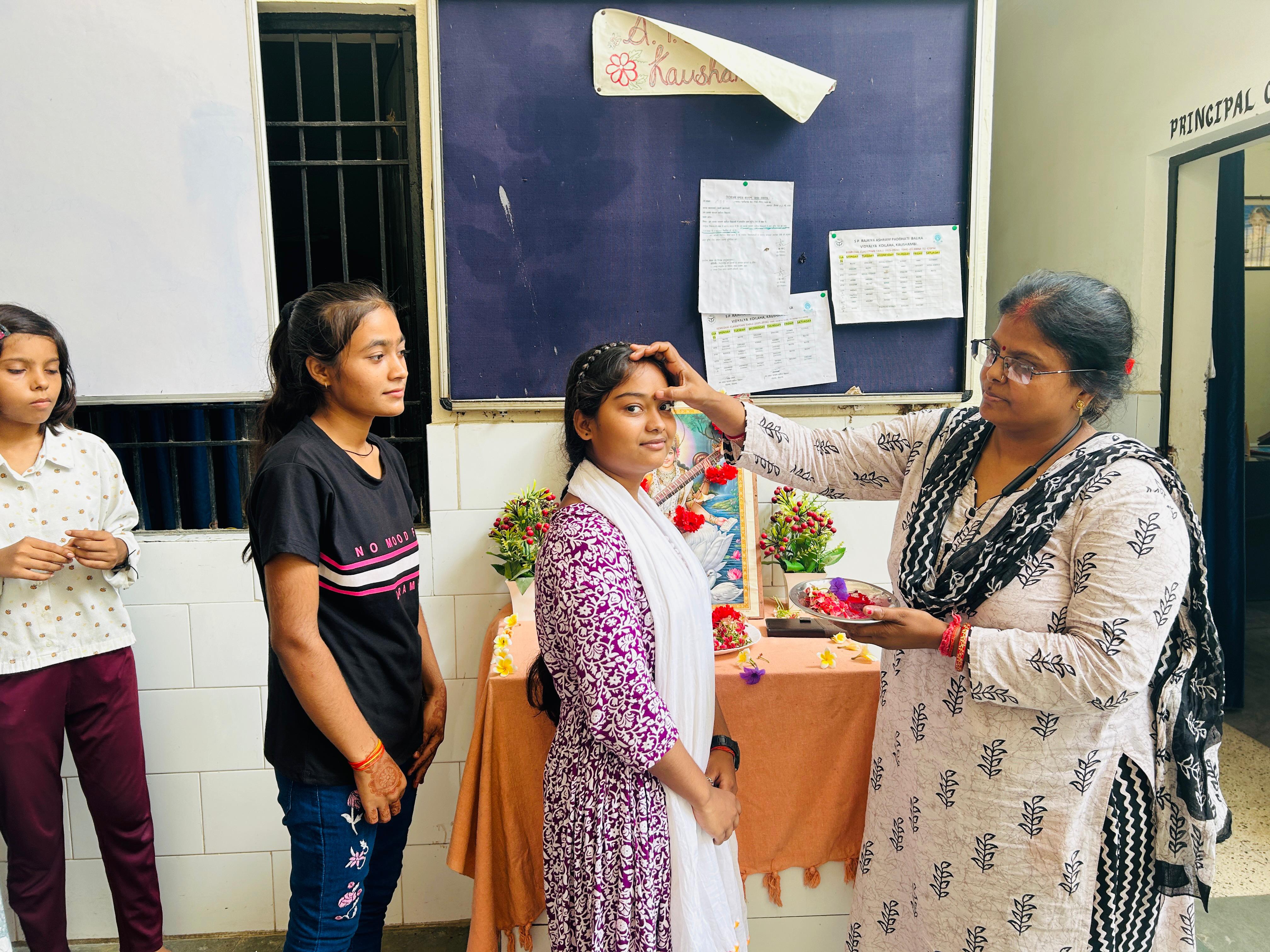 बच्चों का तिलक कर स्वागत करते अध्यापक