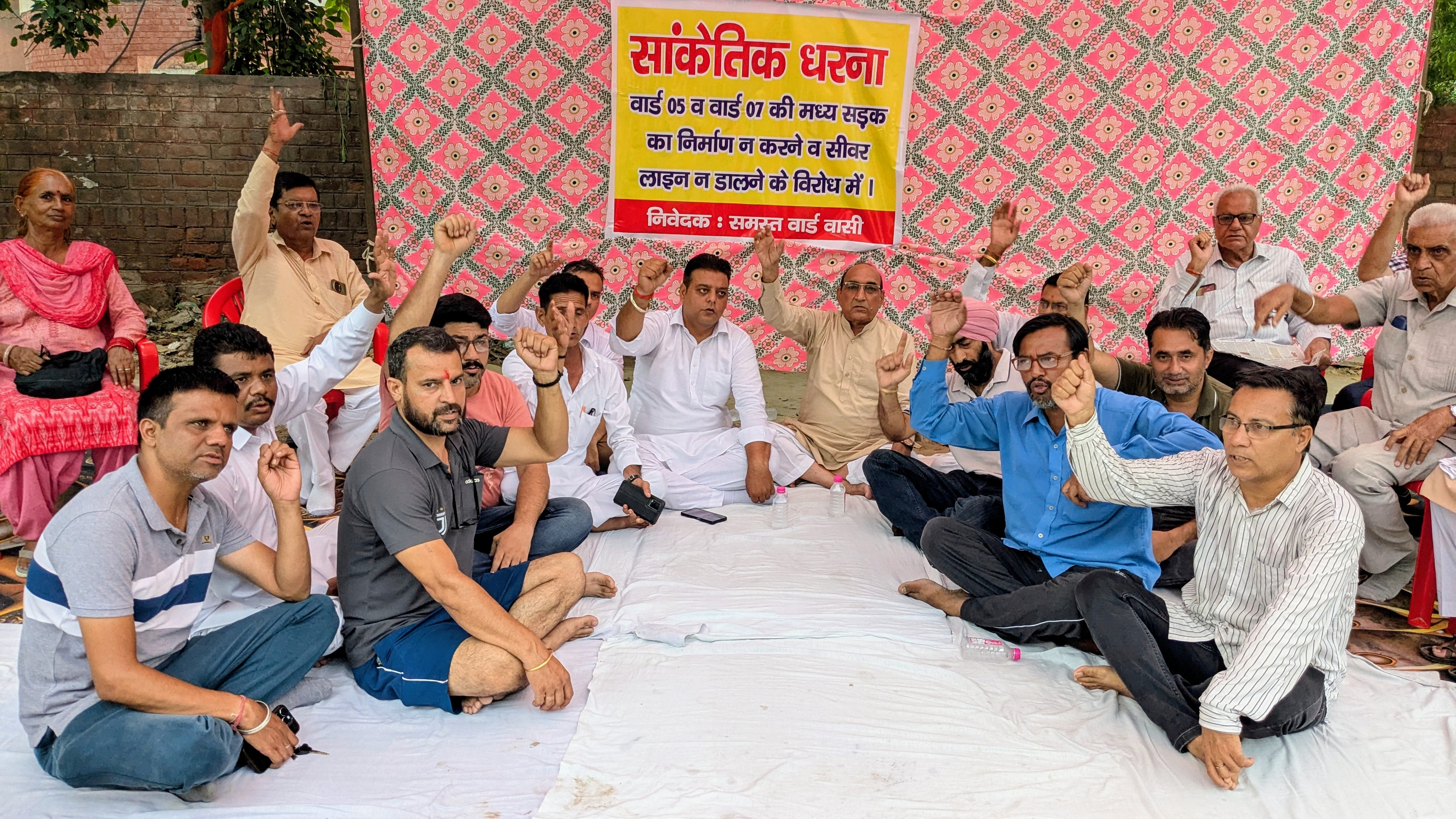 सडक़ व सीवरेज की मांग को लेकर धरने पर बैठे लोग।