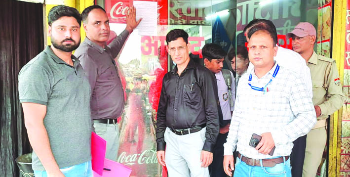 नोटिस चस्पा करते हुए नोटिस चस्पा करते हुए