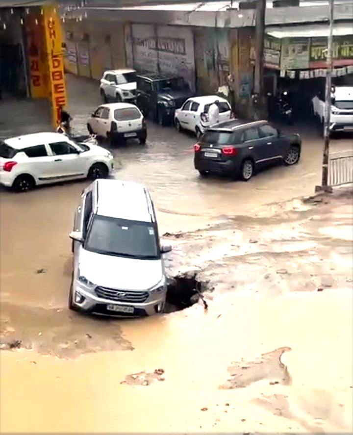 गड्ढे में फंसी एक कार। गड्ढे में फंसी एक कार।