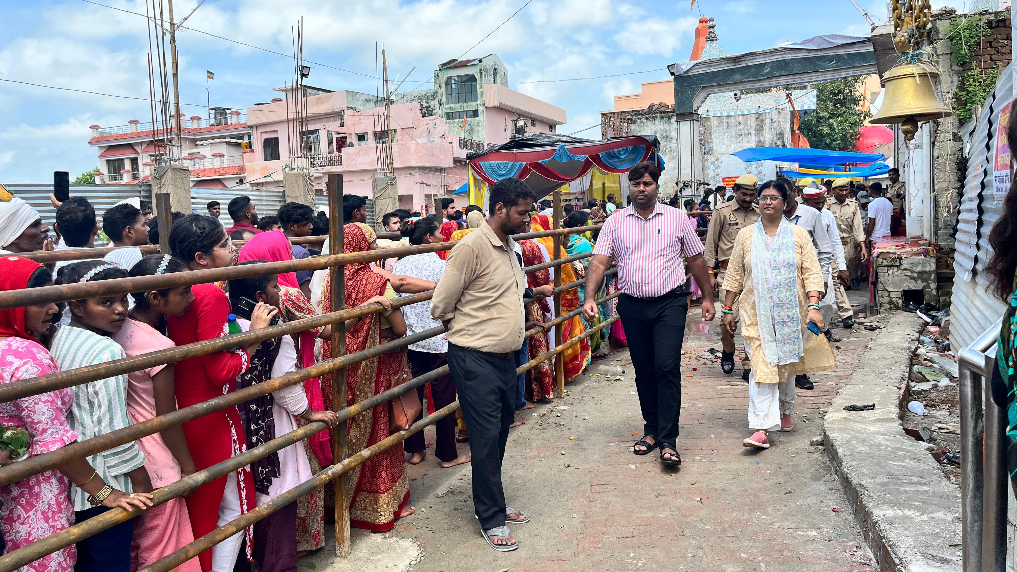 बैरिकेडिंग के रास्ते मंदिर में दर्शन करने जाते भक्त, निरीक्षण करते अधिकारी