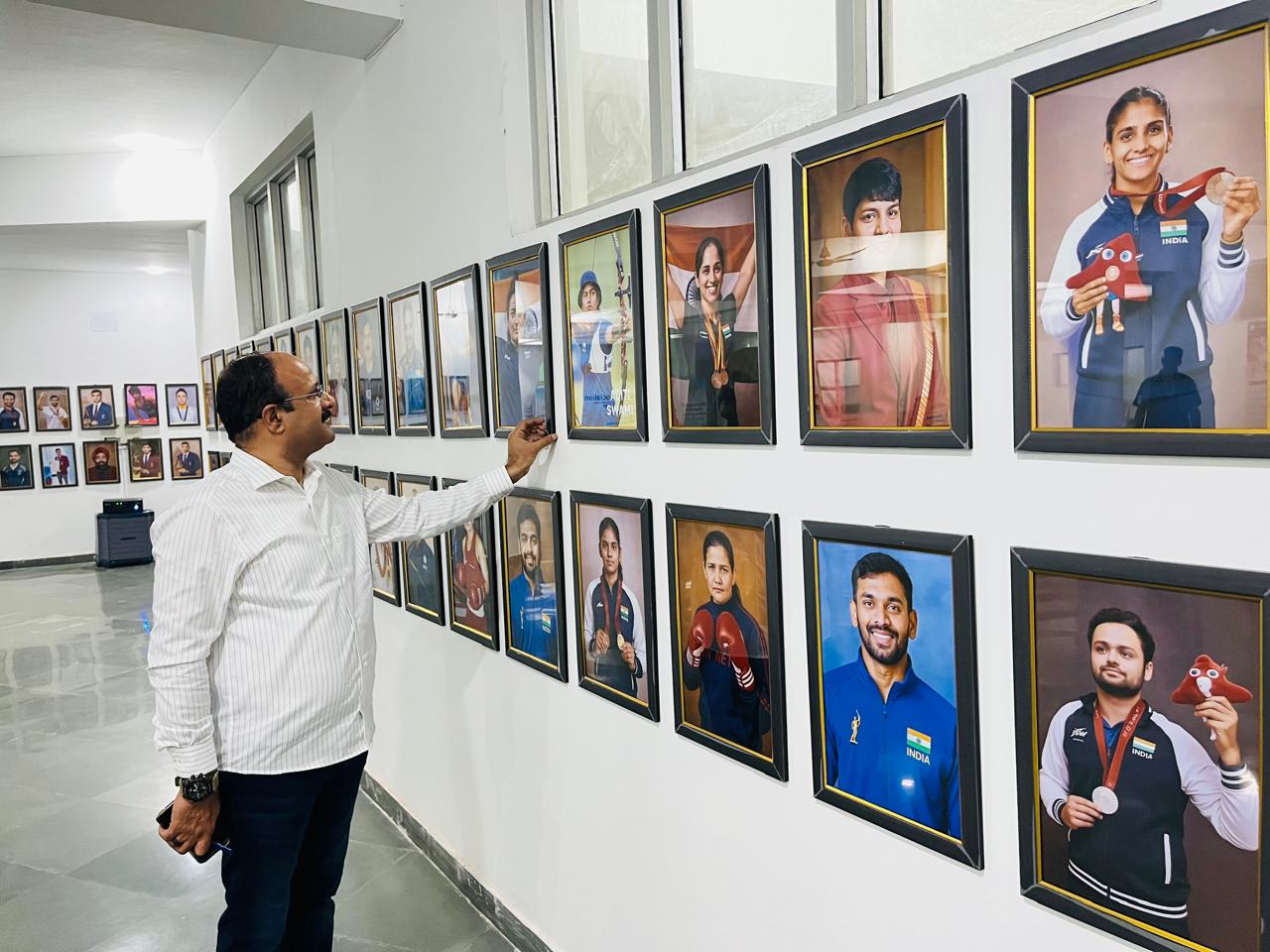 हरियाणा ओलंपिक एसोसएिशन के अध्यक्ष मीनू बैनीवाल खिलाड़ियों की तस्वीरों का अवलोकन करते हुए