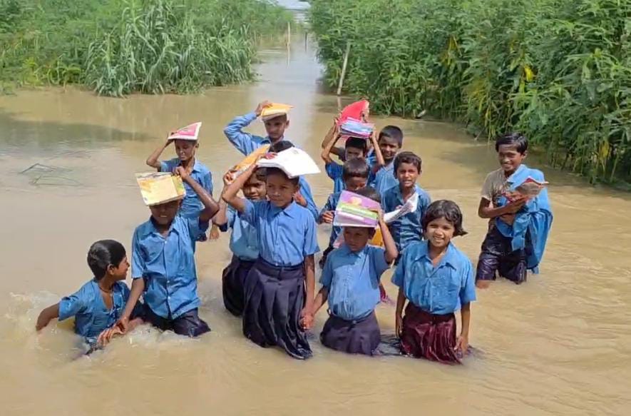 पानी के बीच स्कूल जाते बच्चे पानी के बीच स्कूल जाते बच्चे