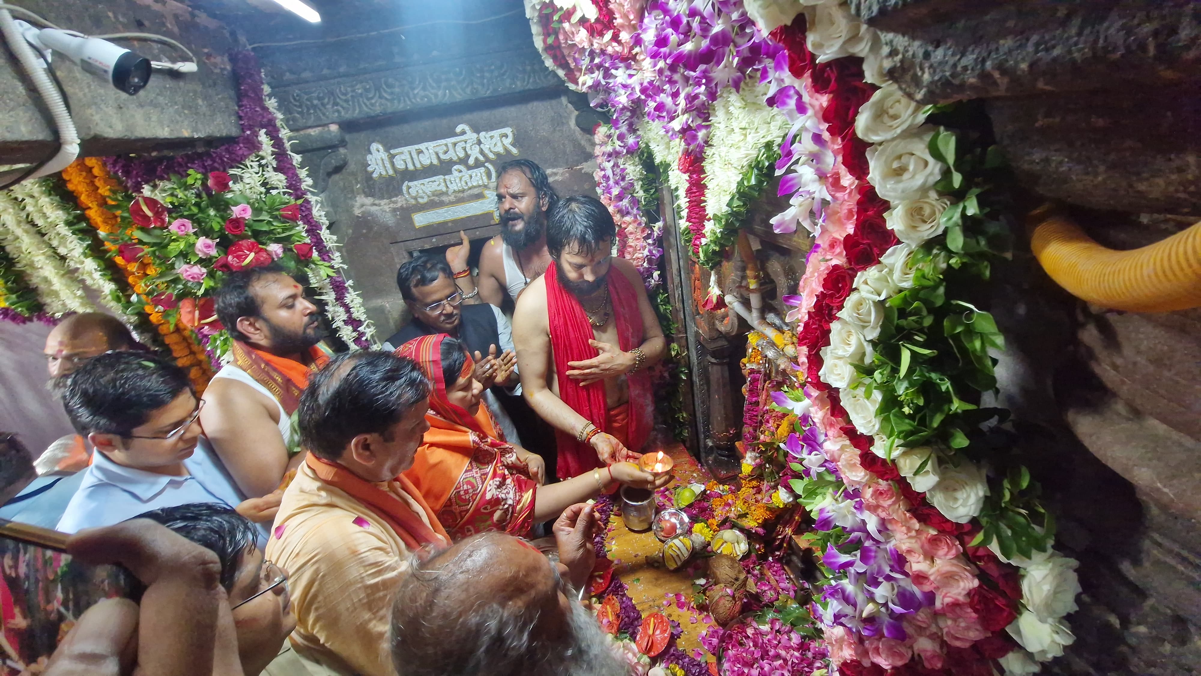 सोमवार रात 12 बजे पंचायती महानिर्वाणी अखाडे के महंत विनितगिरी महाराज की अगुआई में नागचंद्रेश्वर मंदिर के पट खुले। अखाड़े की ओर से पूजन पश्चात आम श्रद्धालुओं के लिए रास्ता खोल दिया गया। महाकाल मंदिर के द्वितीय तल पर स्थित नागचंद्रेश्वर मंदिर के पट वर्ष में एक बार खुलते हैं। रात्रि में पट खुलने के बाद दर्शन का सिलसिला प्रारंभ हो गया,जोकि मंगलवार रात 12 बजे तक जारी रहेगा। सोमवार सुबह से शहर में श्रद्धालुओं की भारी भीड़ उमड़ी। सोमवार की तरह मंगलवार को भी शहर में मिनी कुंभ सा नजारा रहेगा। महाकाल मंदिर, महाकाल महालोक,काल भैरव मंदिर आदि पर श्रद्धालुओं का तांता लगा रहा। इधर सोमवार रात 8 बजे बाद नागचंद्रेश्वर मंदिर में दर्शन के लिए श्रद्धालुओं की कतार लगना शुरू हो गई। कभी रिमझिम तो कभी तेज बारिश के बीच श्रद्धालु कतारों में डटे रहे। रात 12 बजे तक मौसम में काफी ठण्डक घुल गई थी। रात 12 बजे बाद जैसे ही पूजन होकर नागचंदे्रश्वर मंदिर के पट खुले,श्रद्धालुओं के बीच से जयकारे के साथ दर्शन का सिलसिला प्रारंभ हो गया। एक अनुमान है कि मंगलवार को करीब 3 लाख श्रद्धालु नागचंदे्रश्वर मंदिर दर्शन करने पहुचेंगे। उल्लेखनीय है कि नागचन्द्रेश्वर मंदिर में 11 वीं शताब्दीे की एक दुर्लभ प्रतिमा स्थापित है। प्रतिमा में श्री नागचन्द्रेश्वर स्वयं अपने सात फनों से सुशोभित हो रहे है। साथ में शिव-पार्वती के दोनों वाहन नंदी एवं सिंह भी विराजित है। प्रतिमा में श्री गणेश की ललितासन मूर्ति, उमा के दांयी ओर कार्तिकेय की मूर्ति व उपर की ओर सूर्य-चन्द्रमां भी अंकित है। नागचन्द्रेश्वर की मूर्ति अपने आप में भव्य  एवं कलात्मकता का उदहारण है। भगवान के गले और भुजाओं में भुजंग लिपटे हुए है। कहते हैं कि यह प्रतिमा नेपाल से यहां लाई गई थी। ऐसी मान्यता है किए उज्जैेन के अलावा दुनिया में कहीं भी ऐसी प्रतिमा नहीं है। इस प्रतिमा के दर्शन के उपरांत अंदर प्रवेश करने पर भगवान नागचन्द्रेश्वर के शिवलिंग के दर्शन होते है।   आज रात 12 बजे एक वर्ष के लिए बंद होंगे पट नागचंद्रेश्वर मंदिर के पट सोमवार रात 12 बजे खुले,जोकि मंगलवार को रात 12 बजे तक खुले रहेंगे। रात्रि 12 बजे पूजन पश्चात पट एक  वर्ष के लिए बंद हो जाएंगे। नागचन्द्रेश्वर की त्रिकाल पूजा अन्तर्गत सोमवार मध्यरात्रि मेें पट खुलने के पश्चा्त पंचायती महानिर्वाणी अखाडे के महंत विनितगिरी महाराज द्वारा प्रथम पूजन व अभिषेक किया गया। मंगलवार दोपहर 12 बजे अखाडे द्वारा पूजन किया जाएगा। इसीप्रकार महाकालेश्वर मंदिर प्रबंध समिति द्वारा मंगलवार सायं पूजन-आरती महाकालेश्वर मंदिर के पुजारी एवं पुरोहितों द्वारा की जाएगी।