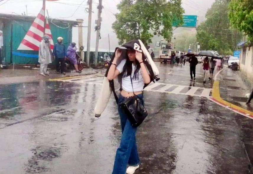 नैनीताल में बारिश के दौरान माल रोड पर गुजरती एक युवती। नैनीताल में बारिश के दौरान माल रोड पर गुजरती एक युवती।