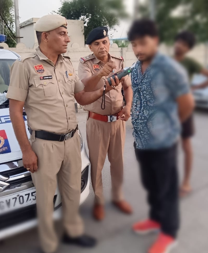 कार चालक का ब्रेथ एनालाइजर से एल्कोहल टैस्ट करते पुलिस अधिकारी। कार चालक का ब्रेथ एनालाइजर से एल्कोहल टैस्ट करते पुलिस अधिकारी।