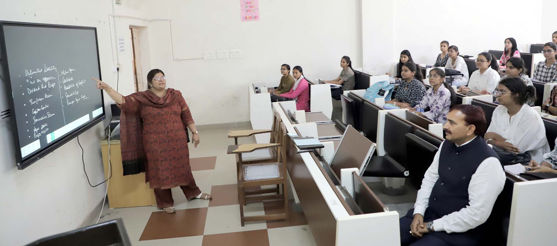 वाणिज्य विभाग में कक्षा कक्ष में विद्यार्थियों के बीच बैठकर कक्षा संचालन का निरीक्षण करते कुलपति प्रो. नरसीराम बिश्नोई।