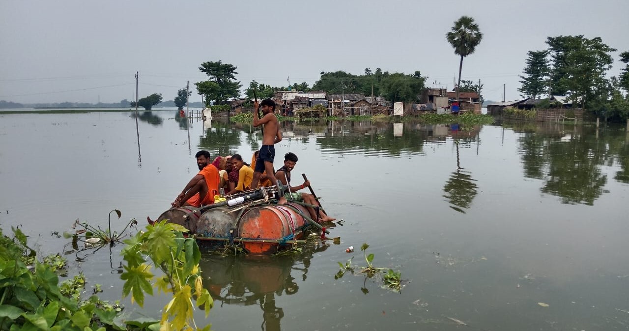 ड्रम के नाव पर पार करते लोग