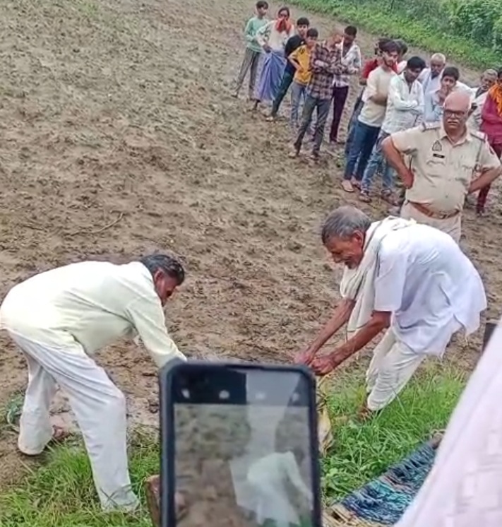 खेत पर कुएं से बोरियां निकालते लोग