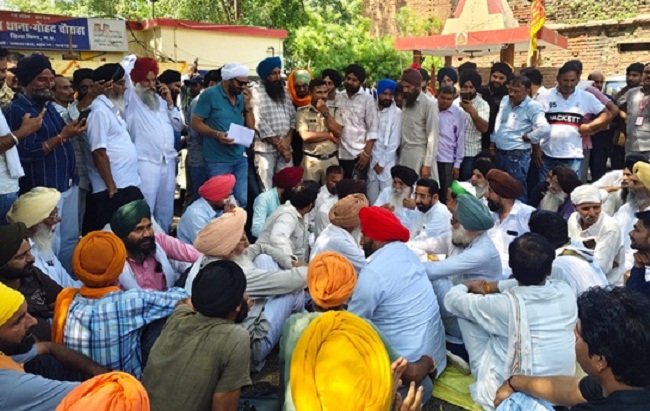 एनआरआई परिवार पर हमले के विरोध में थाने का घेराव कर धरने पर बैठे समाज जन