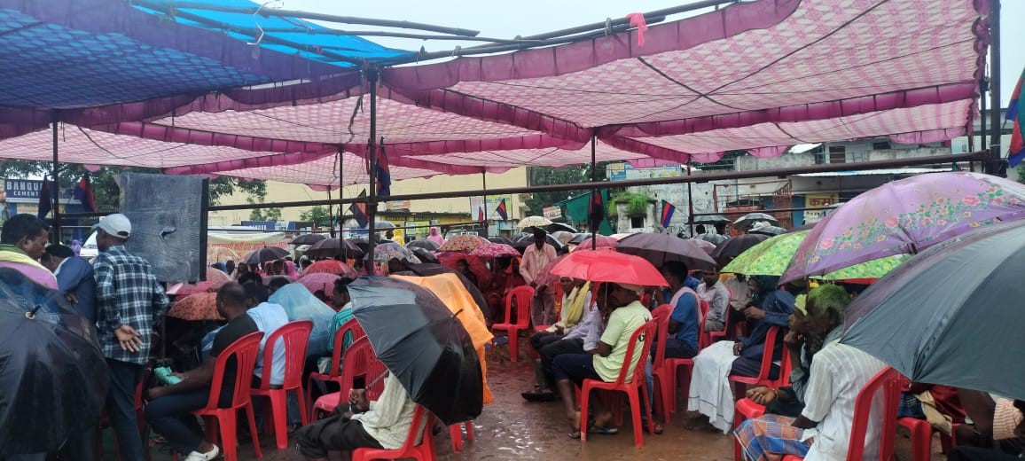 छतरी के साथ धरना प्रदर्शन में लोगों की भीड़।
