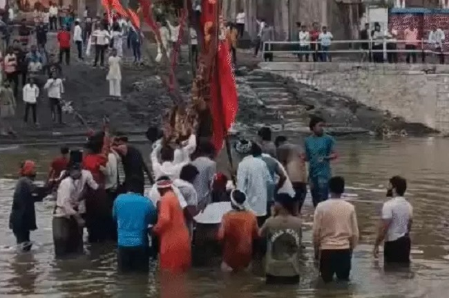 जाम नदी के बीच में लगे झंडे और चंडी माता का पूजन करते लोग
