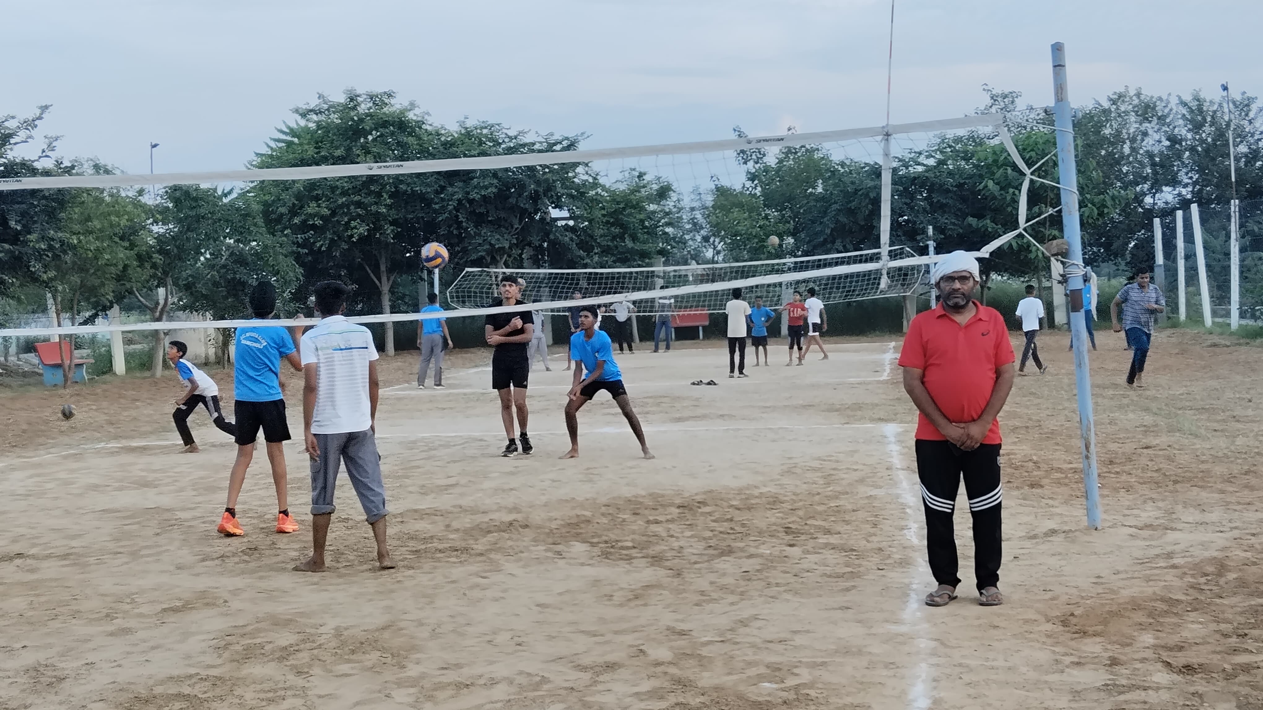 स्टेडियम में वॉलीबॉल मैच खेलते युवा।