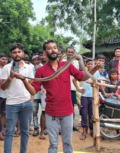 हथेडा गाँव में घर में निकले सांप को पकडकर ले जाते विवेक मिश्र।