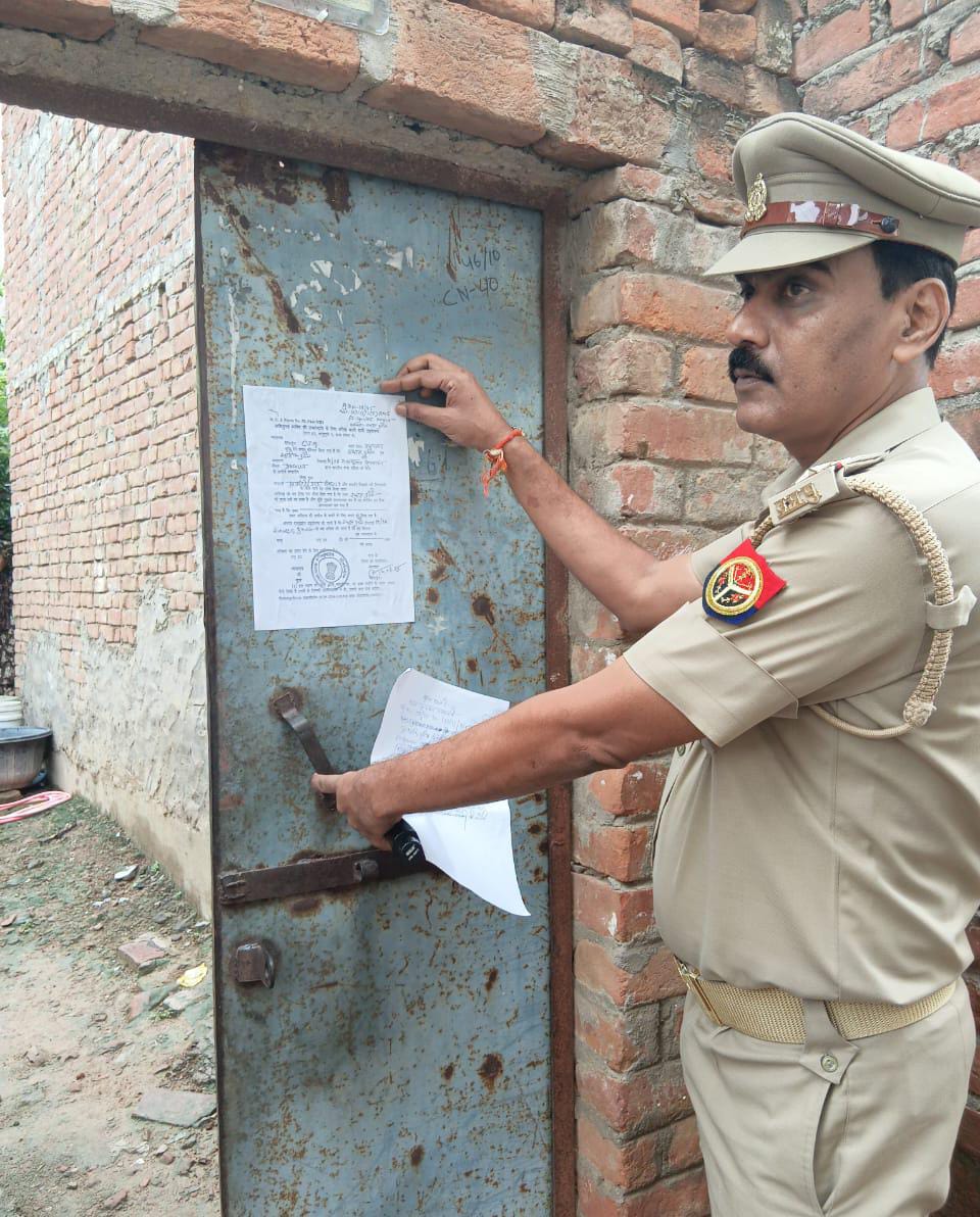 हत्यारोपित के घर कुर्की की नोटिस चस्पा करते हुए पुलिस टीम का छाया चित्र हत्यारोपित के घर कुर्की की नोटिस चस्पा करते हुए पुलिस टीम का छाया चित्र