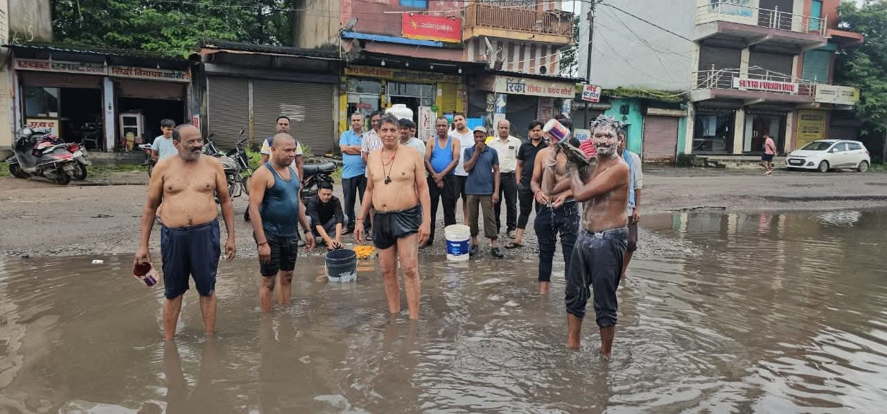 सड़क के गड्ढों में भरे पानी से नहाकर व्यापारियों ने जताया विरोध सड़क के गड्ढों में भरे पानी से नहाकर व्यापारियों ने जताया विरोध