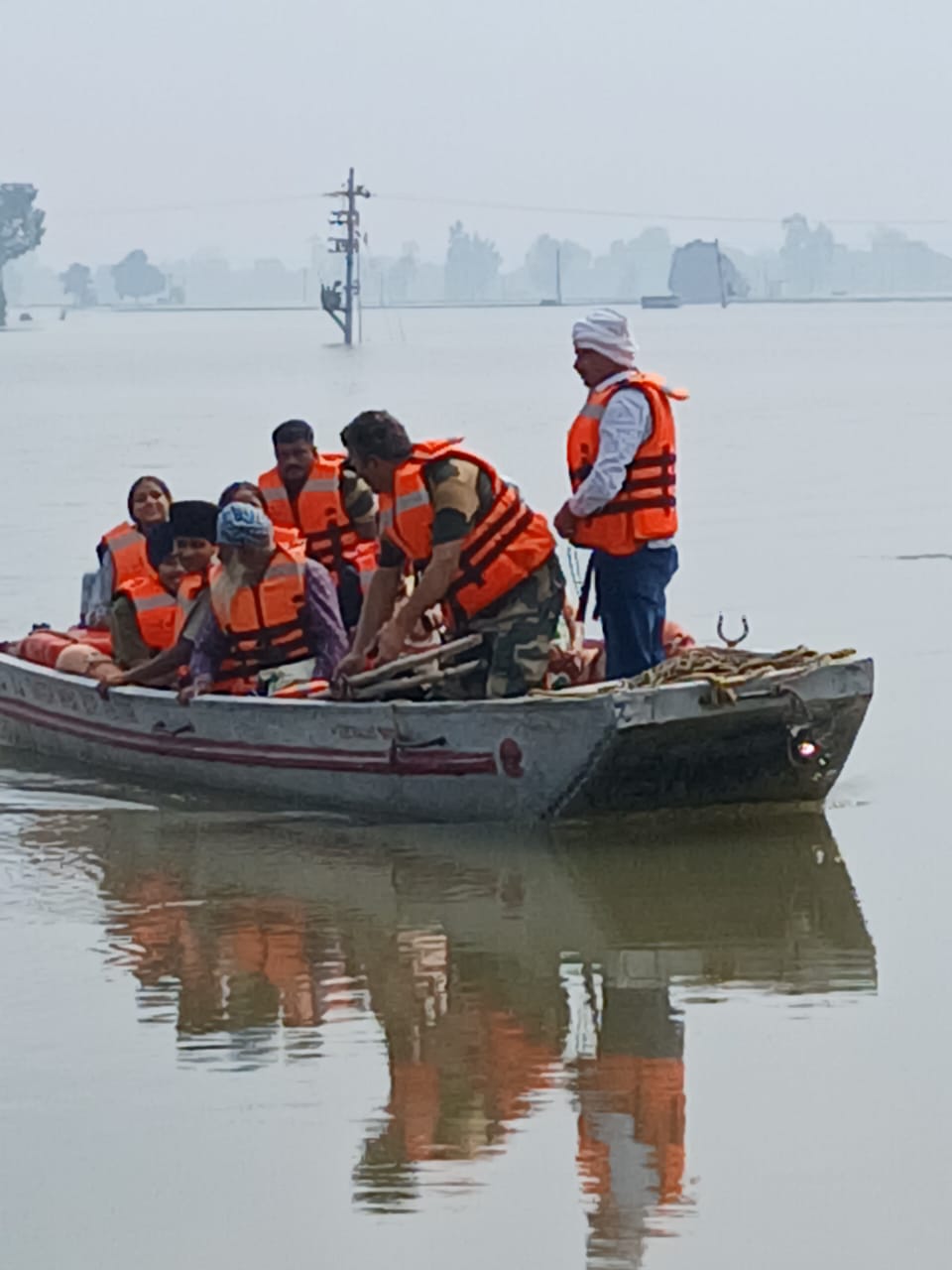 पंजाब में बाढ़ में फंसे लाेगाें काे बाहर निकालते राहत दल के सदस्य