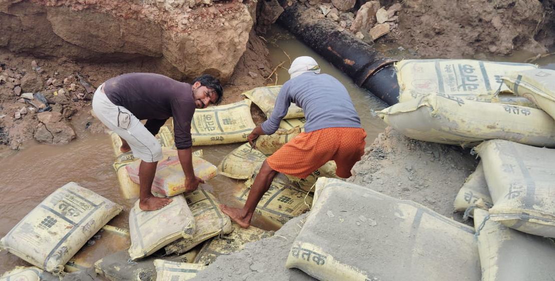 सिमेन्ट की बोरी से सड़क के गढ्ढों को भरते ग्रामीण। सिमेन्ट की बोरी से सड़क के गढ्ढों को भरते ग्रामीण।