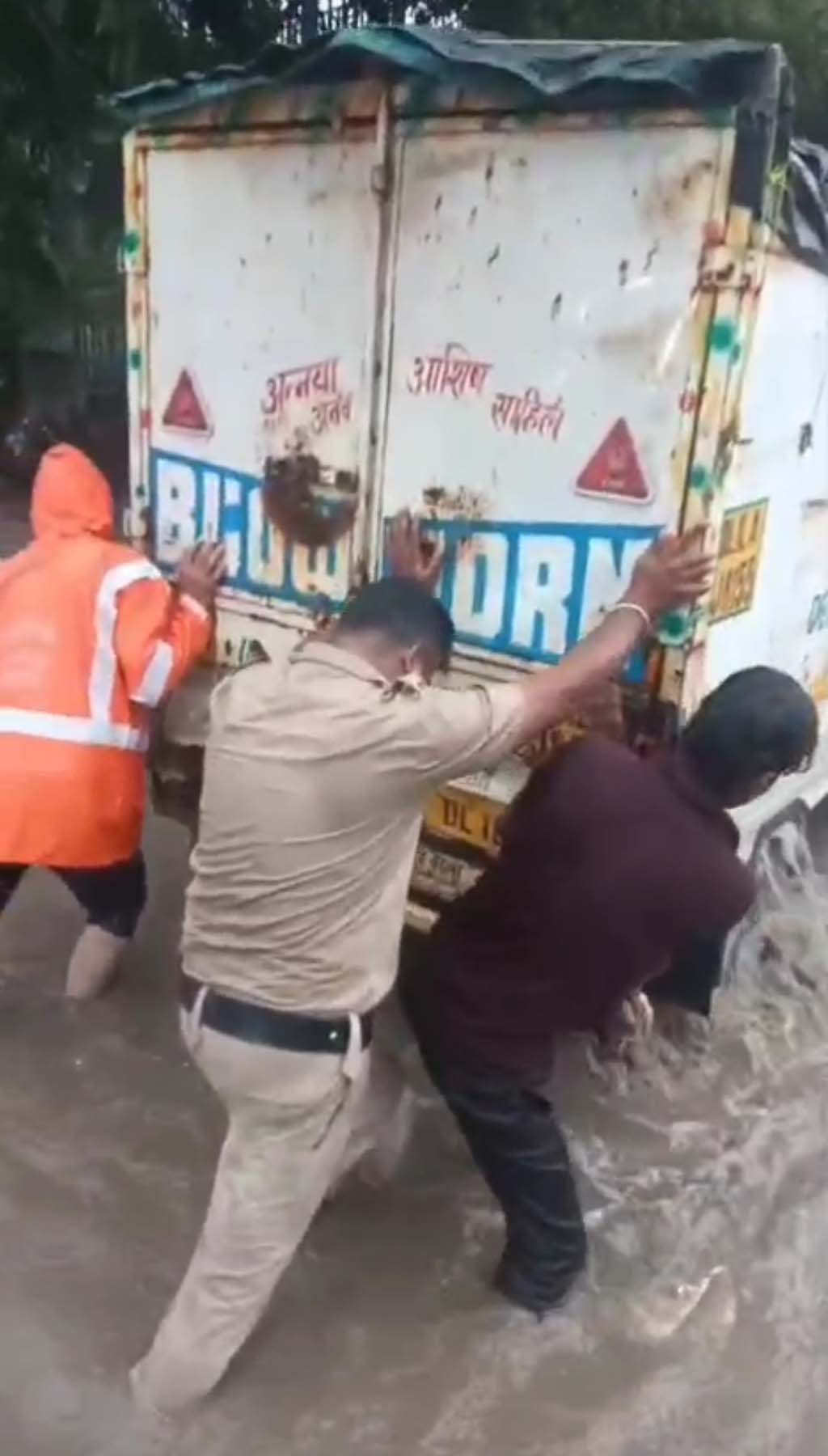 गुरुग्राम में बरसाती पानी में फंसे वाहन को धक्के लगाकर निकलवाते पुलिसकमी।