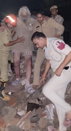 सब्ज़ी मंडी में इमारत गिरने के बाद लोगों को बचते हुए पुलिसकर्मियों की फोटो