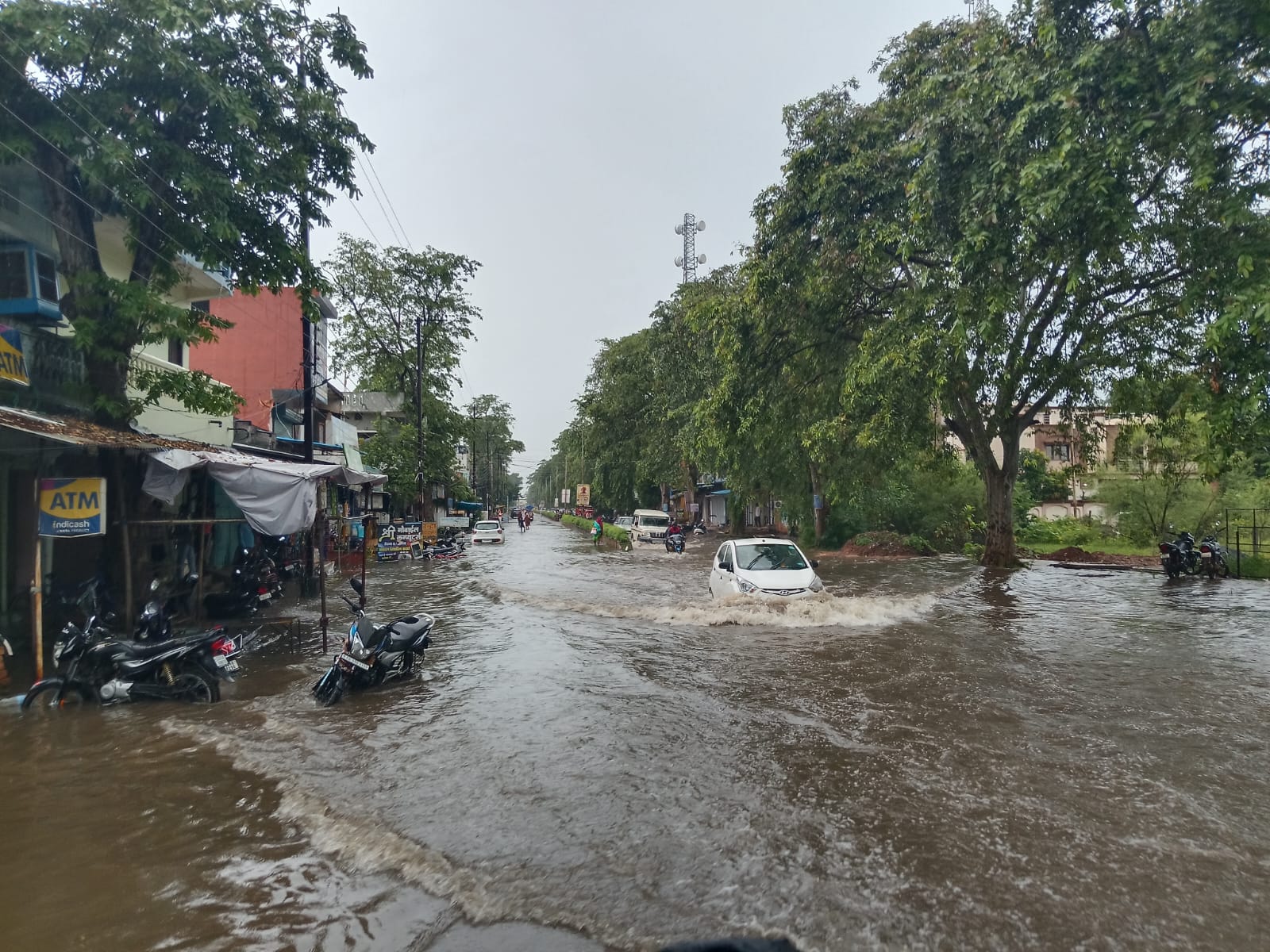 वर्षा के बाद सड़क में भरे पानी से निकलता हुआ वाहन