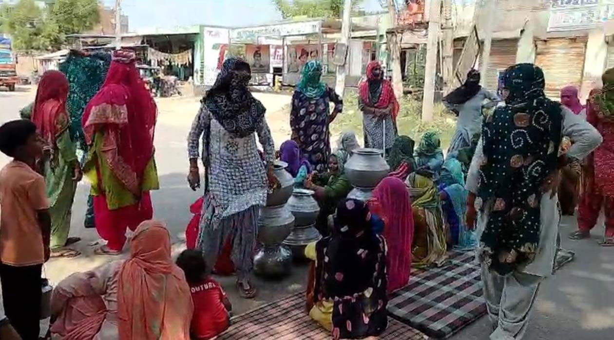 सड़क जाम के दौरान खाली बर्तन लेकर सड़क पर बैठी महिलाएं।