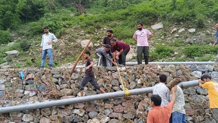 धर्मपुर में जल परियोजनाओं को ठीक करते कर्मचारी।