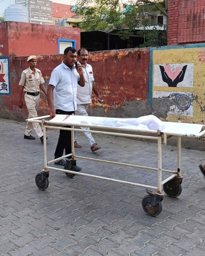 बच्ची के शव को शव गृह में ले जाते हुए स्वास्थ्यकर्मी।