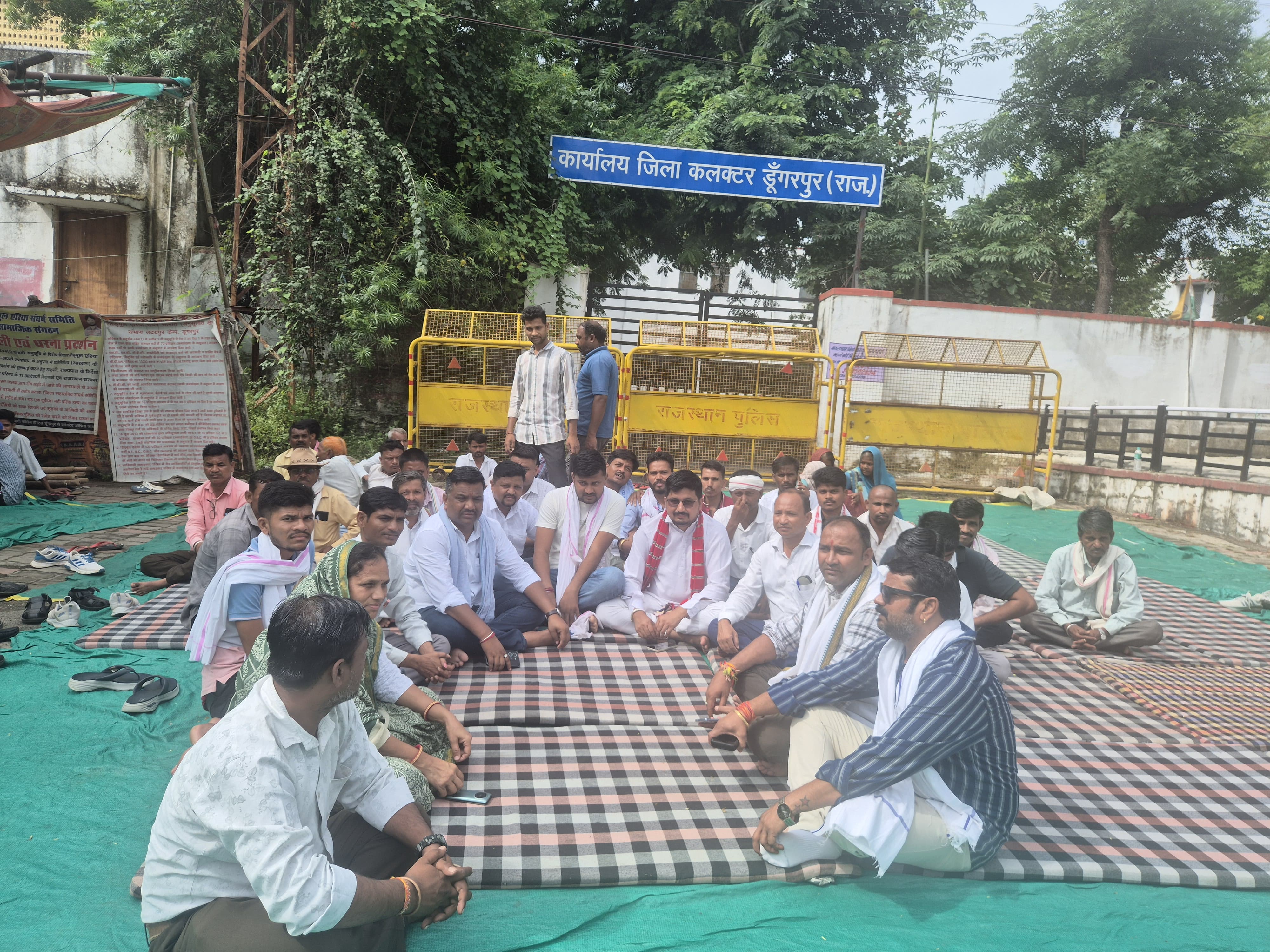 कलेक्ट्रेट के बाहर तीसरे दिन धरना देते हुए जनप्रतिनिधि एवं आदिवासी समाज के लोग