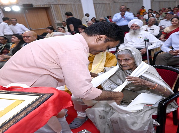 बुजुर्ग ​महिला का सम्मान करते असीम अरुण