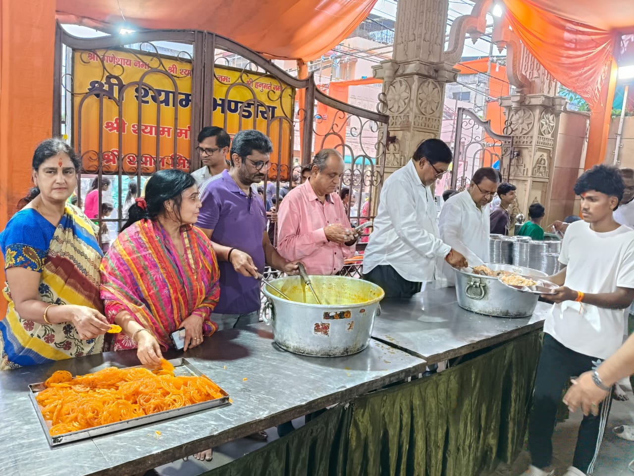 श्रद्धालुओं के बीच प्रसाद वितरण करते मंच के लोग